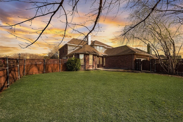 yard at dusk featuring a gate and a fenced backyard