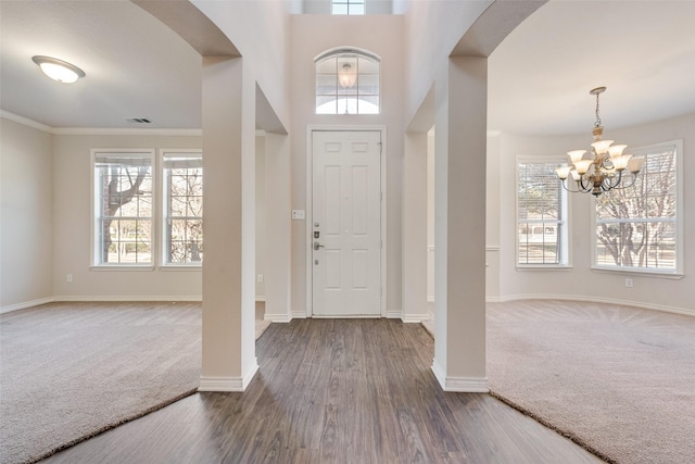 entrance foyer featuring visible vents, a healthy amount of sunlight, arched walkways, and carpet floors