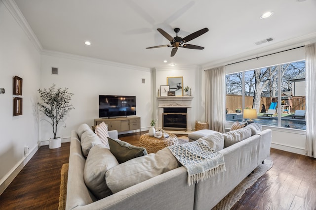 living room featuring a glass covered fireplace, wood finished floors, visible vents, and ornamental molding