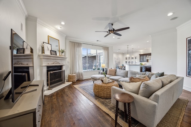 living room featuring crown molding, recessed lighting, a fireplace with raised hearth, and dark wood-style flooring