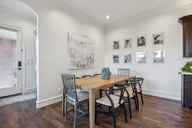 dining area with baseboards, wood finished floors, arched walkways, and ornamental molding