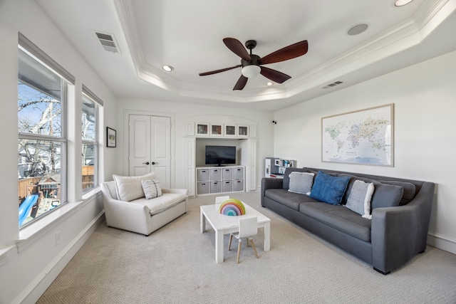 carpeted living room with visible vents, a raised ceiling, and ornamental molding