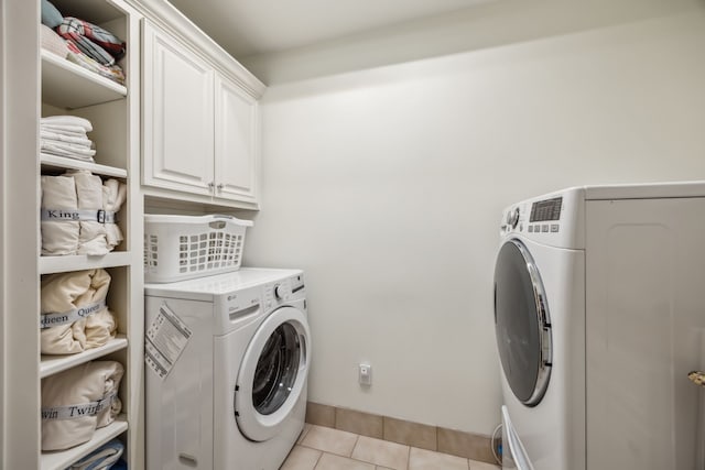 laundry area featuring light tile patterned flooring, cabinet space, and washing machine and clothes dryer