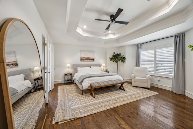 bedroom featuring a raised ceiling, wood finished floors, baseboards, and ornamental molding