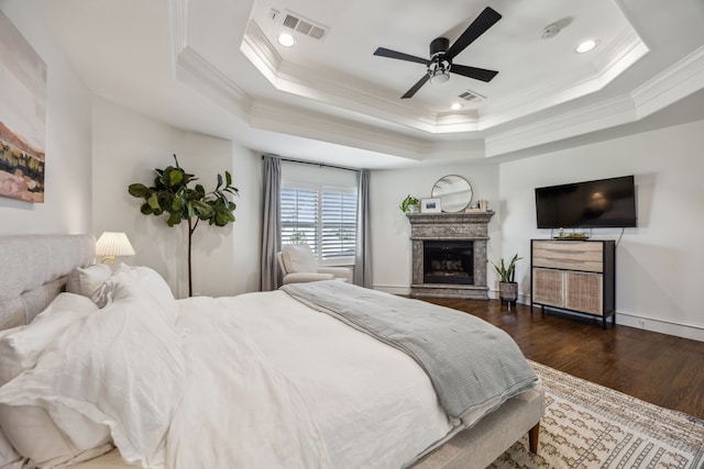 bedroom with a tray ceiling, dark wood-style floors, and visible vents