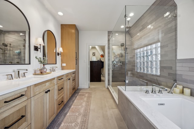 bathroom featuring a shower stall, a garden tub, double vanity, and a sink