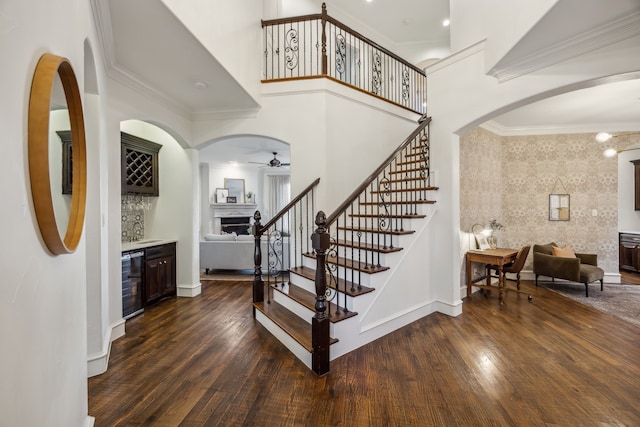 staircase featuring beverage cooler, ornamental molding, a dry bar, and hardwood / wood-style flooring