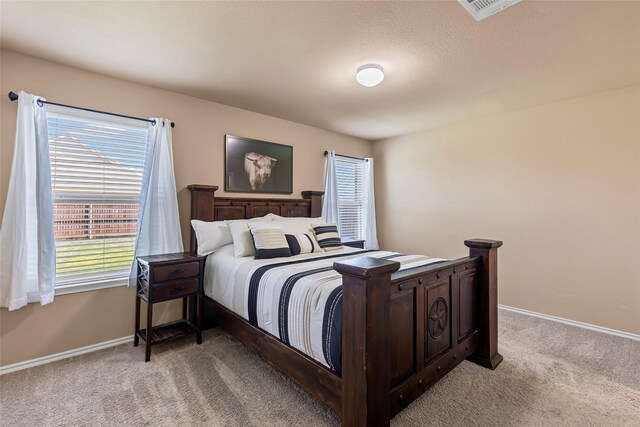 bedroom featuring visible vents, baseboards, and light carpet