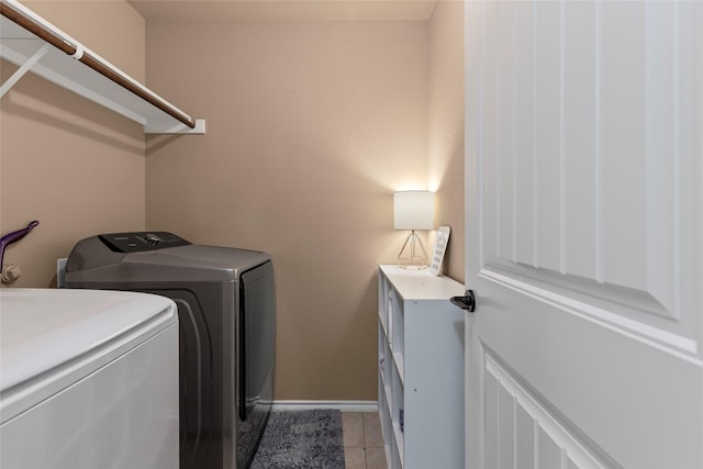 washroom with washer and dryer, baseboards, light tile patterned flooring, and laundry area