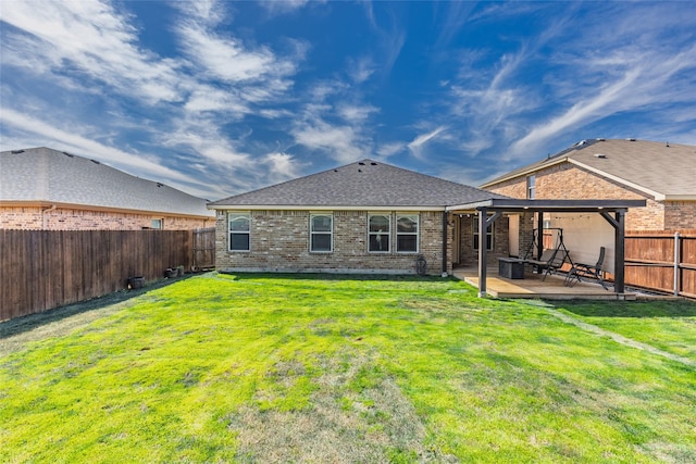 rear view of property with brick siding, a lawn, a patio, and a fenced backyard