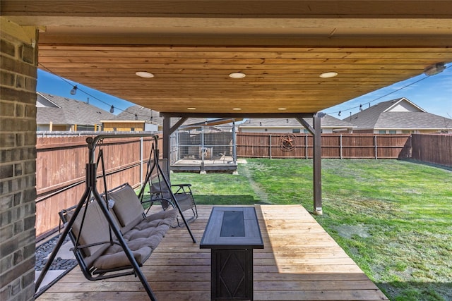 deck featuring a lawn, a fenced backyard, and an outdoor fire pit