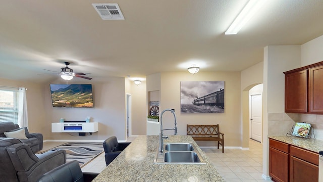 kitchen featuring visible vents, open floor plan, arched walkways, a ceiling fan, and a sink