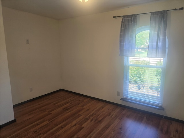spare room featuring baseboards and dark wood-style floors
