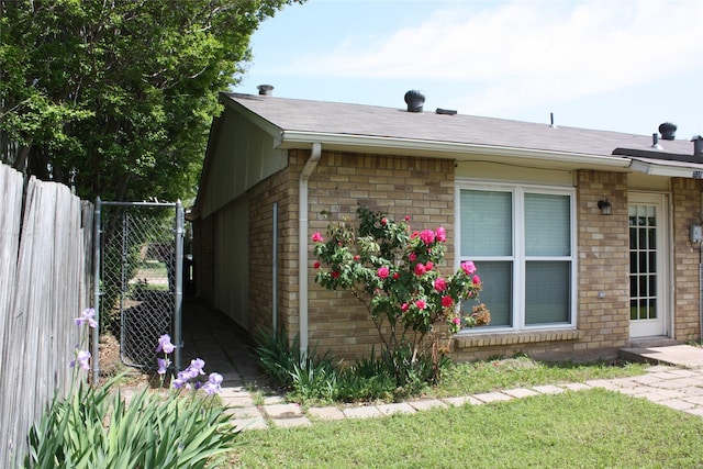view of property exterior with brick siding, fence, and a gate