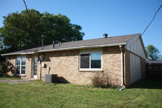 back of house with cooling unit, a yard, fence, and brick siding