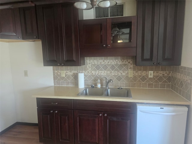 kitchen with dishwasher, light countertops, a sink, and backsplash