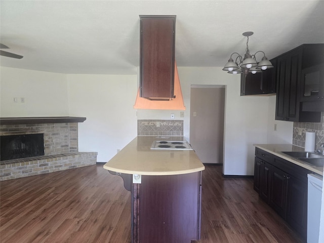 kitchen with white dishwasher, dark wood-style flooring, light countertops, and backsplash