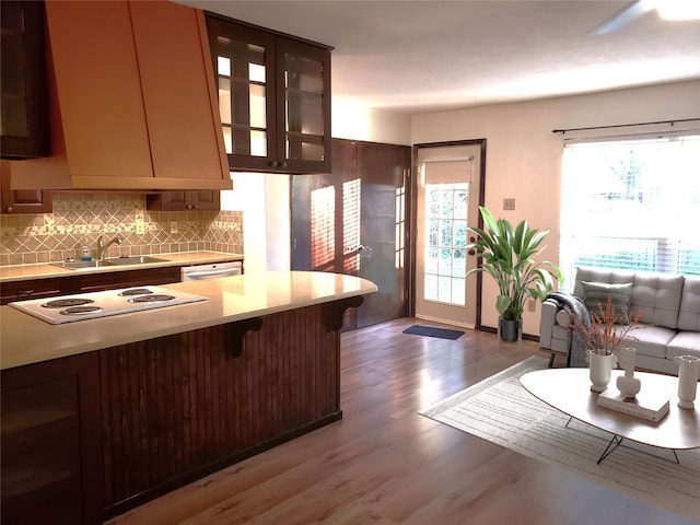 kitchen featuring a sink, light countertops, a breakfast bar, light wood finished floors, and decorative backsplash