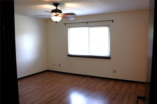 spare room with baseboards, ceiling fan, and wood finished floors