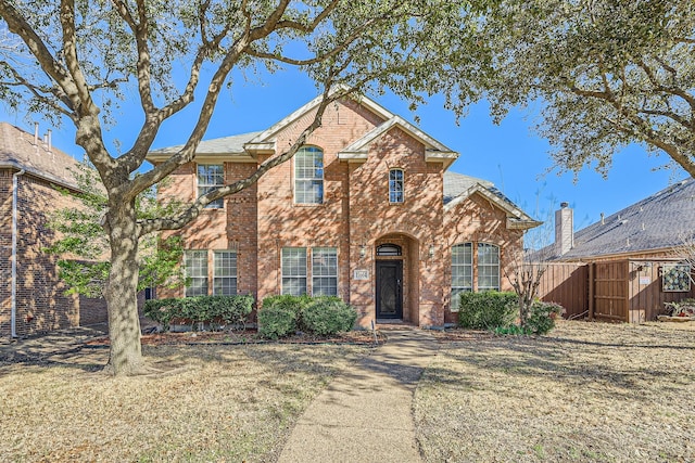 traditional-style home with fence and brick siding