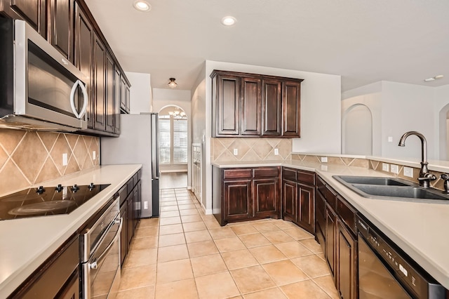 kitchen with a sink, stainless steel appliances, arched walkways, light tile patterned flooring, and light countertops