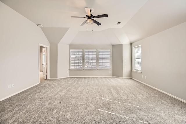 empty room with carpet flooring, visible vents, baseboards, and vaulted ceiling