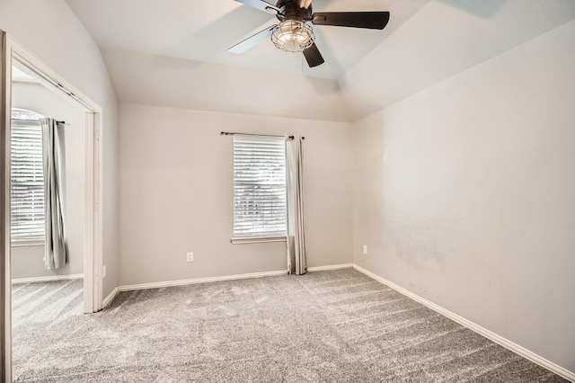 carpeted empty room featuring lofted ceiling, baseboards, and ceiling fan