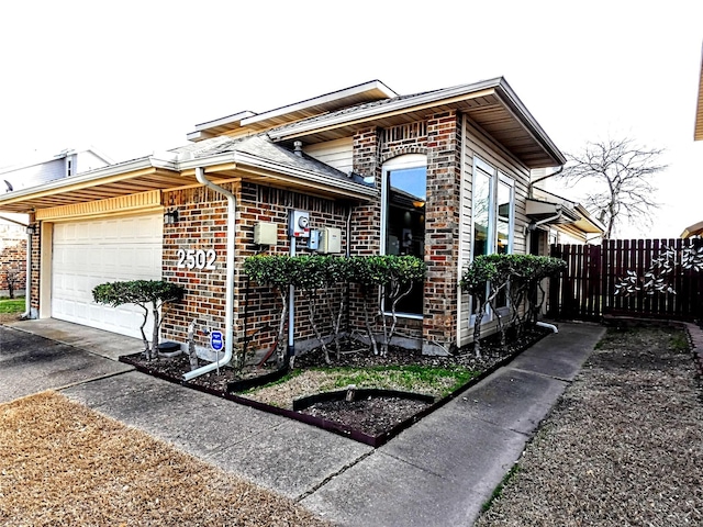 view of front of house featuring brick siding, a garage, and fence