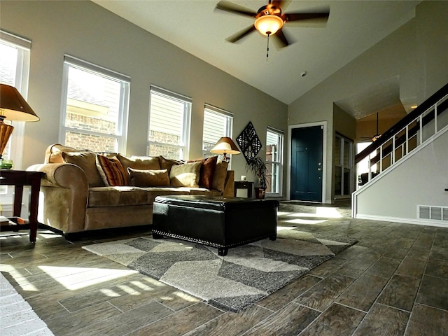 living area with visible vents, ceiling fan, wood tiled floor, stairs, and high vaulted ceiling