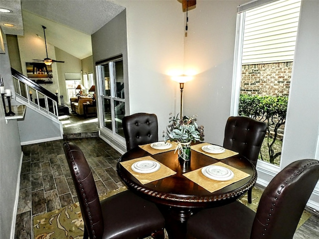 dining area with stairway, plenty of natural light, wood tiled floor, and vaulted ceiling