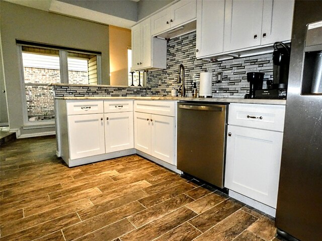 kitchen featuring backsplash, white cabinets, appliances with stainless steel finishes, and a peninsula