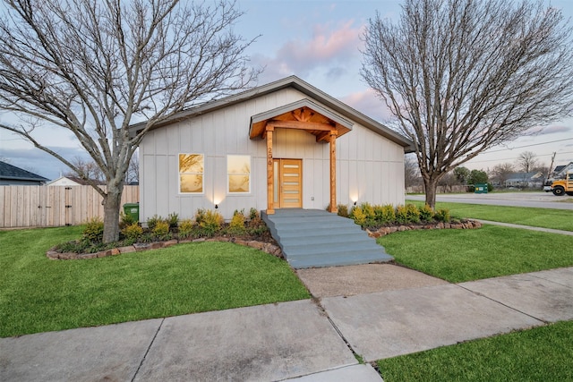 view of front of home with a lawn and fence