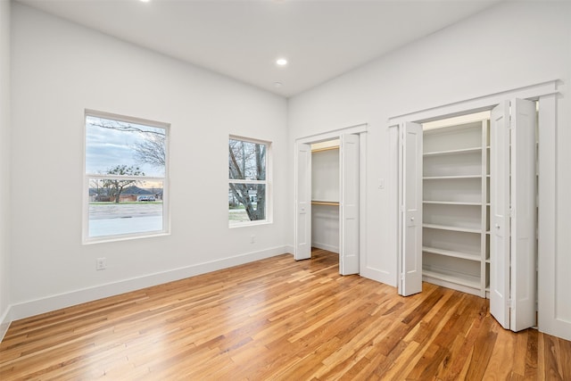 unfurnished bedroom featuring recessed lighting, light wood-type flooring, multiple closets, and baseboards