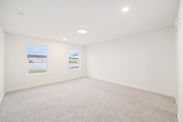 spare room with recessed lighting, light colored carpet, and baseboards