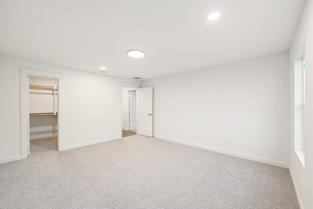 unfurnished bedroom with baseboards, carpet floors, and a walk in closet