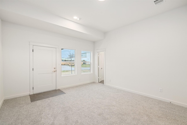 carpeted spare room featuring baseboards and visible vents