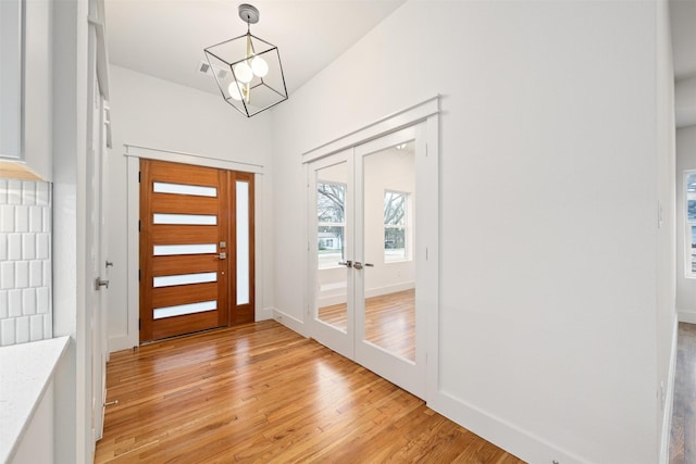 entrance foyer featuring light wood finished floors, visible vents, french doors, and baseboards