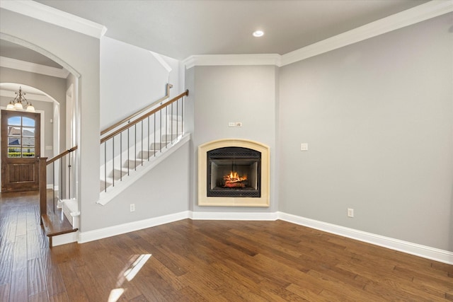 unfurnished living room with baseboards, an inviting chandelier, arched walkways, stairs, and hardwood / wood-style flooring