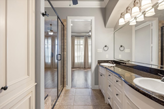 bathroom featuring a shower stall, crown molding, ceiling fan, double vanity, and a sink