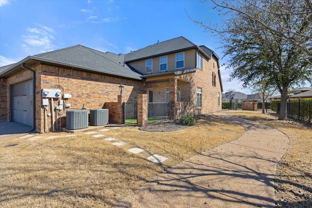 rear view of property with a gate, a garage, central AC, and fence