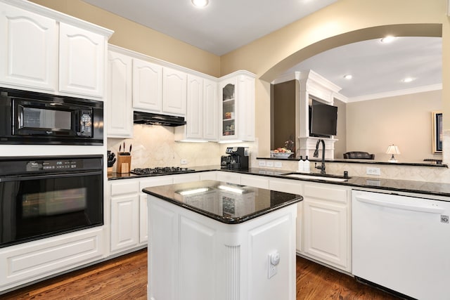 kitchen with dark wood finished floors, under cabinet range hood, white cabinets, black appliances, and a sink