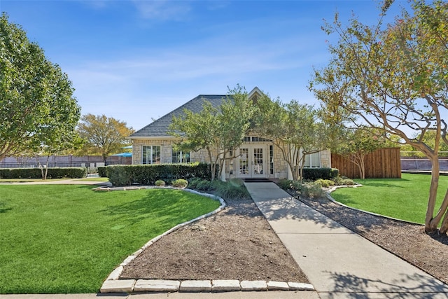 view of front of property featuring a front lawn, fence, roof with shingles, french doors, and stone siding