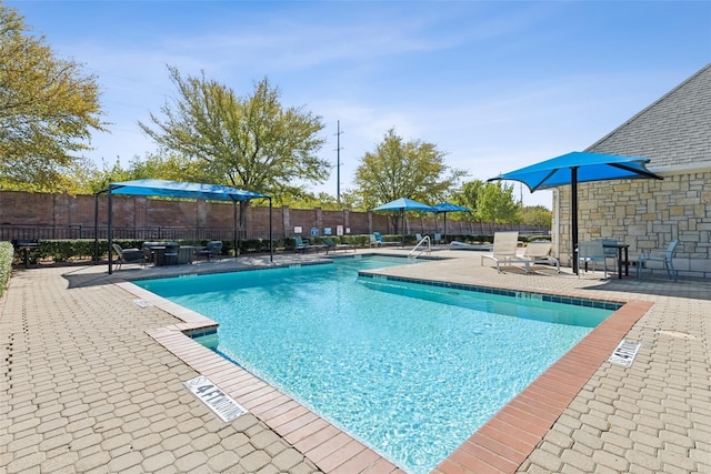 community pool with a patio area and fence