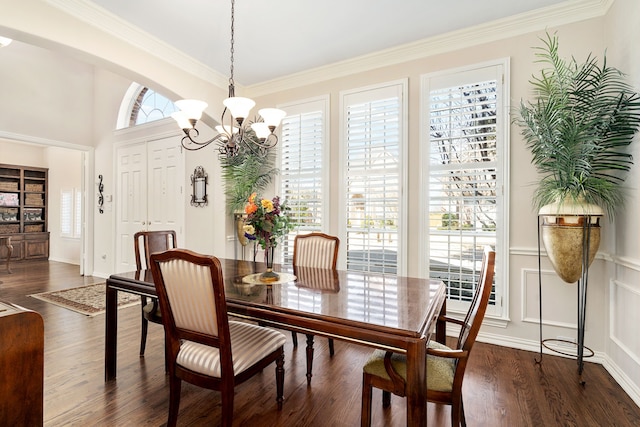 dining space featuring dark wood-type flooring, a chandelier, ornamental molding, arched walkways, and a decorative wall