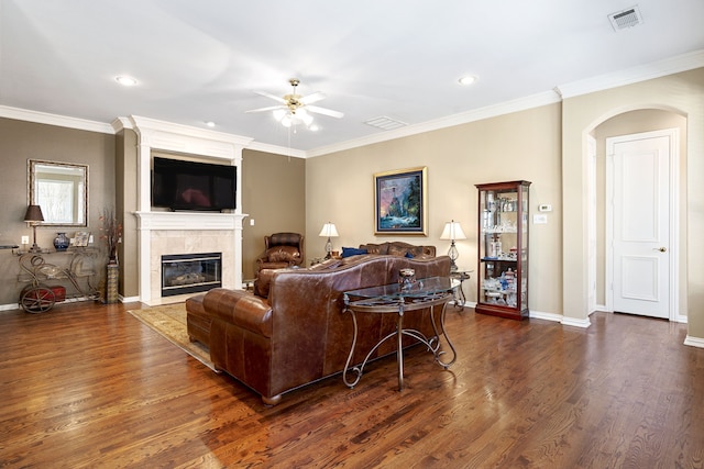 living room featuring visible vents, baseboards, dark wood-type flooring, and a tiled fireplace