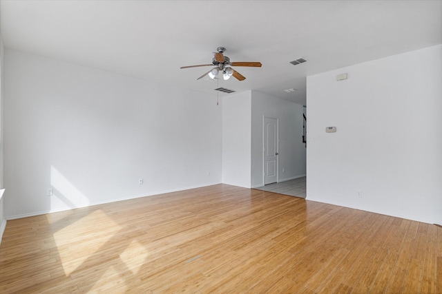 empty room featuring light wood finished floors, visible vents, and ceiling fan