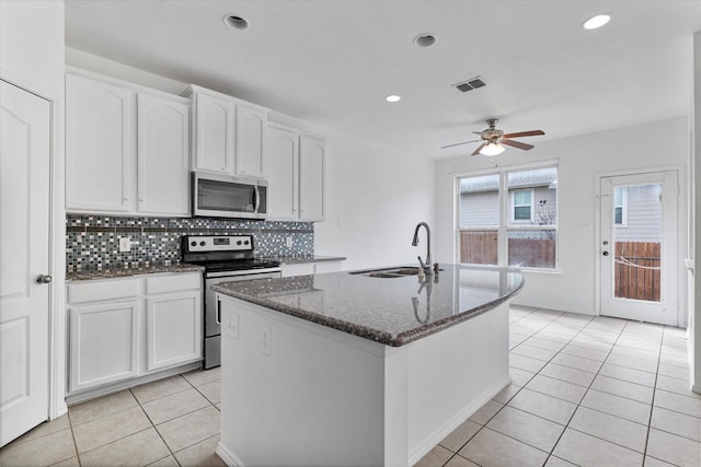 kitchen with visible vents, a sink, dark stone counters, appliances with stainless steel finishes, and light tile patterned flooring