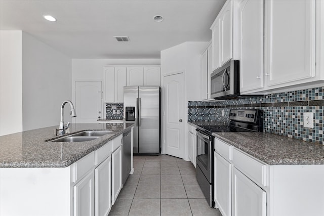 kitchen featuring visible vents, an island with sink, a sink, dark stone countertops, and appliances with stainless steel finishes