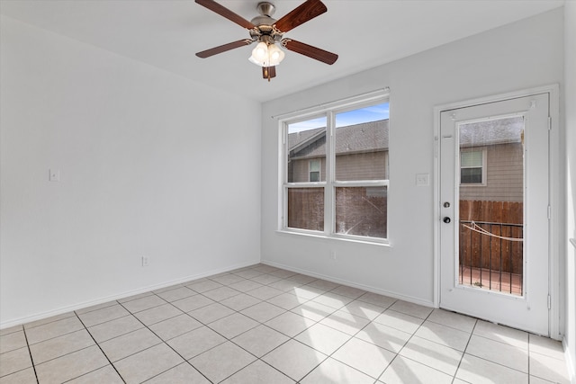 spare room with light tile patterned floors, a ceiling fan, and baseboards