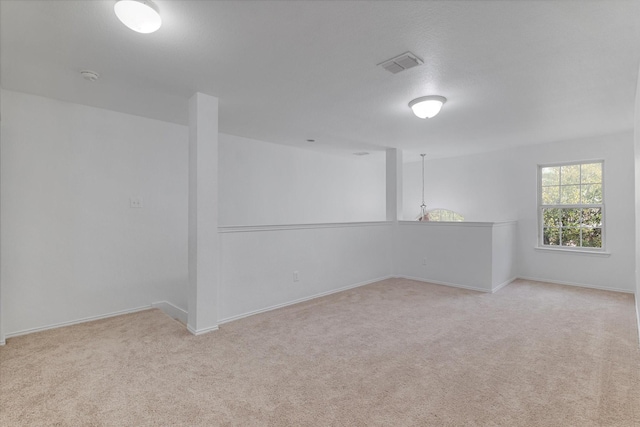 empty room featuring visible vents, baseboards, and light colored carpet